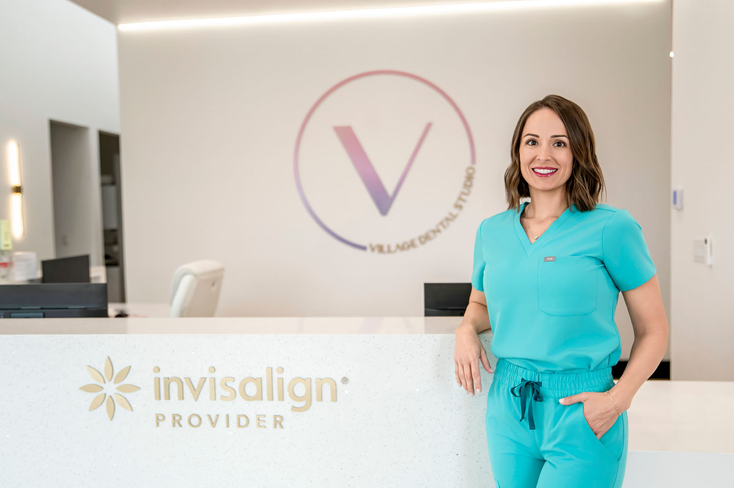 Dr. Traci Leon in blue scrubs standing at the Village Dental Studio Invisalign counter