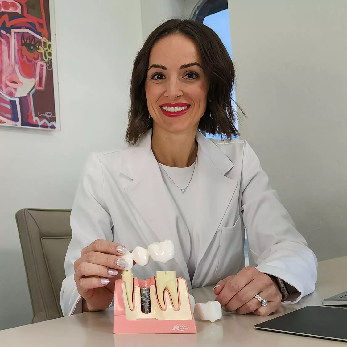 Dr. Traci Leon with a dental bridge model